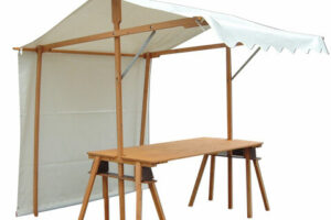 Ein Markstand mit weißer Plane und einer zwei Meter breiten Tischfläche aus Holz. Man kann ihn benutzen um Waren auf einem Wochenmarkt zu präsentieren oder um Speisen anzubieten